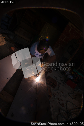 Image of welder with protective mask welding steel