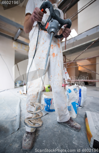 Image of construction worker mixing plaster in bucket