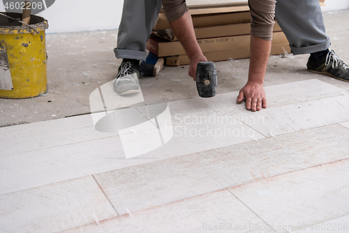 Image of worker installing the ceramic wood effect tiles on the floor