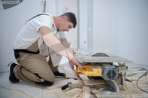 Image of Man cutting laminate floor plank with electrical circular saw