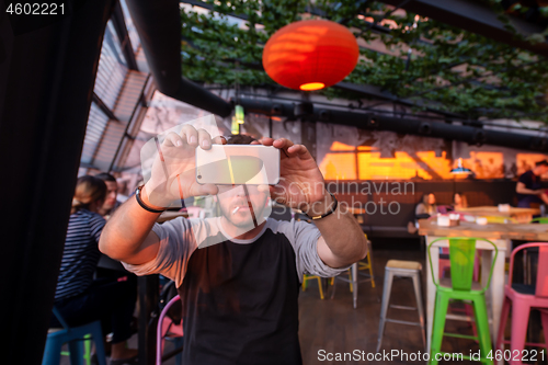 Image of man taking picture in cafe decorate with hanging plant