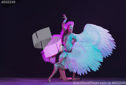 Image of Young female dancers with angel\'s wings in neon light on black background