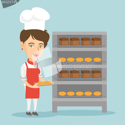 Image of Young caucasian baker holding a tray with bread.