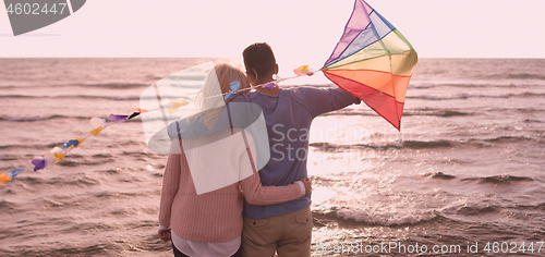 Image of Happy couple having fun with kite on beach