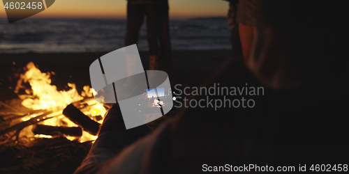 Image of Couple taking photos beside campfire on beach