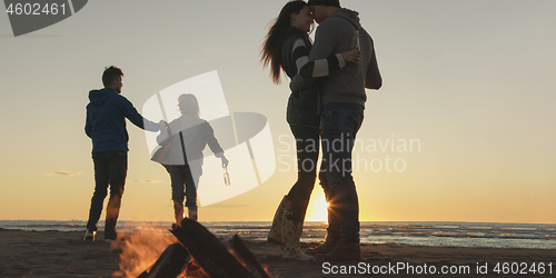 Image of Friends having fun at beach on autumn day