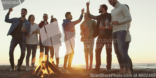 Image of Friends having fun at beach on autumn day