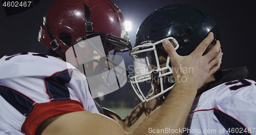 Image of American football players knocking with helmets and having fun