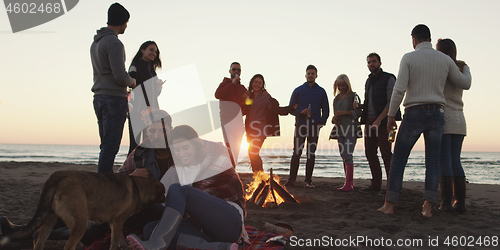 Image of Friends having fun at beach on autumn day