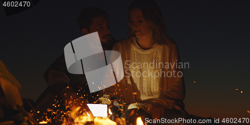 Image of Couple enjoying with friends at night on the beach