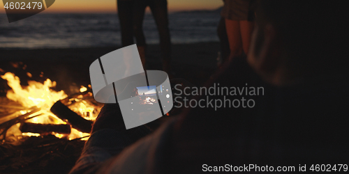 Image of Couple taking photos beside campfire on beach