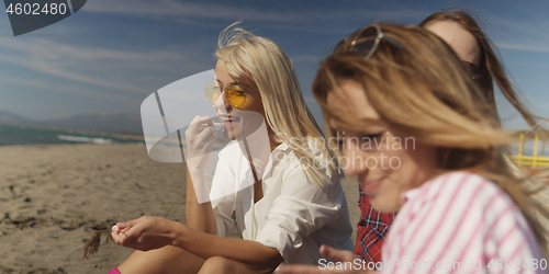 Image of Group of girlfriends having fun on beach during autumn day