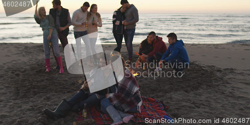 Image of Friends having fun at beach on autumn day