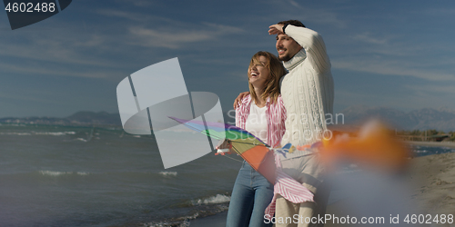 Image of Happy couple having fun with kite on beach