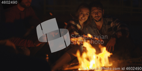 Image of Couple enjoying with friends at night on the beach