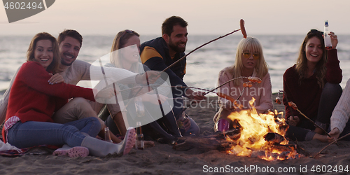 Image of Group Of Young Friends Sitting By The Fire at beach