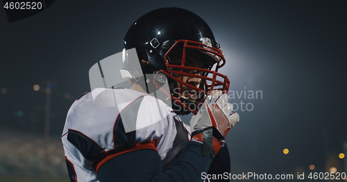 Image of American Football Player Putting On Helmet on large stadium with