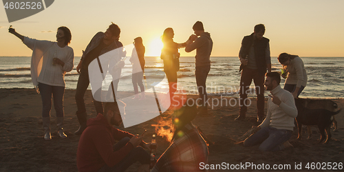 Image of Friends having fun at beach on autumn day