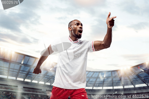 Image of The football player in motion on the field of stadium