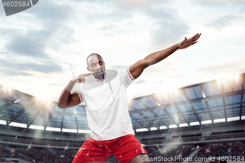 Image of The football player in motion on the field of stadium