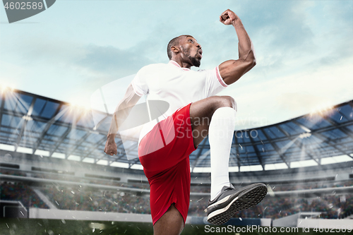 Image of The football player in motion on the field of stadium