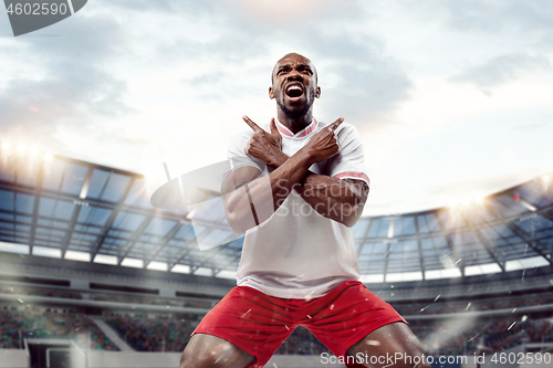 Image of The football player in motion on the field of stadium