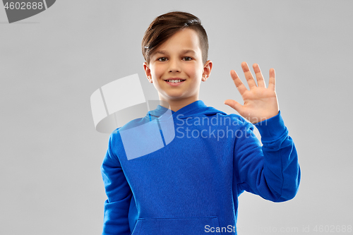 Image of smiling boy in blue hoodie waving hand