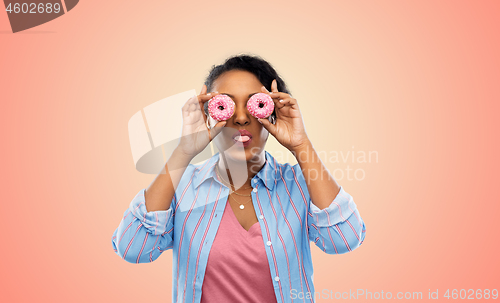 Image of happy african american woman with eyes of donuts