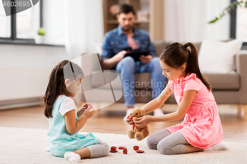 Image of girls playing with toy crockery and teddy at home