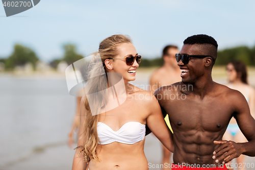 Image of happy friends or couples hugging on summer beach