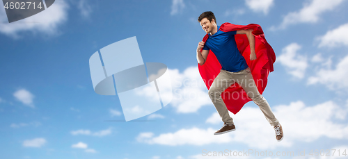 Image of man in red superhero cape flying over sky