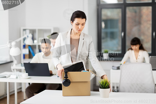 Image of sad female office worker packing personal stuff