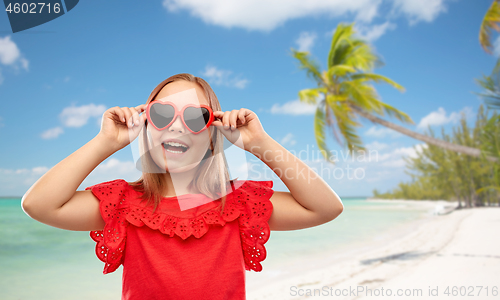 Image of happy girl with heart shaped sunglasses on beach