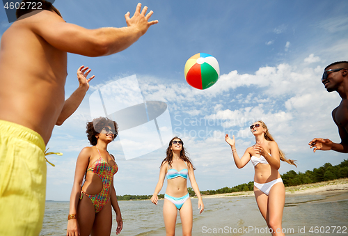 Image of happy friends playing ball on summer beach