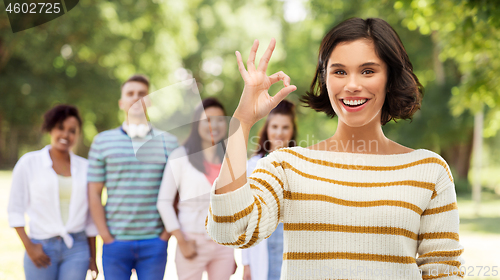 Image of happy smiling woman showing ok over summer park