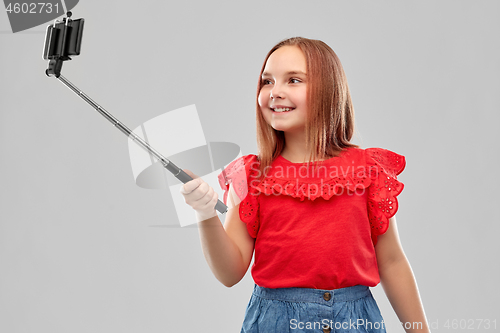 Image of girl taking picture by smartphone on selfie stick