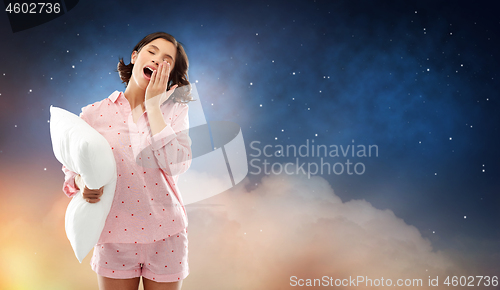 Image of sleepy yawning young woman in pajama with pillow