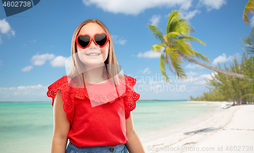 Image of smiling girl with heart shaped sunglasses on beach