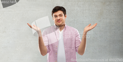 Image of young man shrugging over grey concrete wall