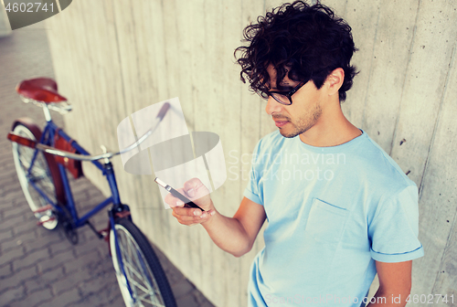 Image of man with smartphone and fixed gear bike on street