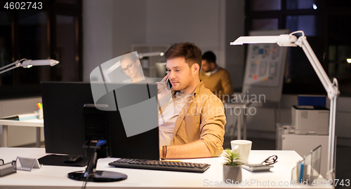 Image of man calling on smartphone at night office