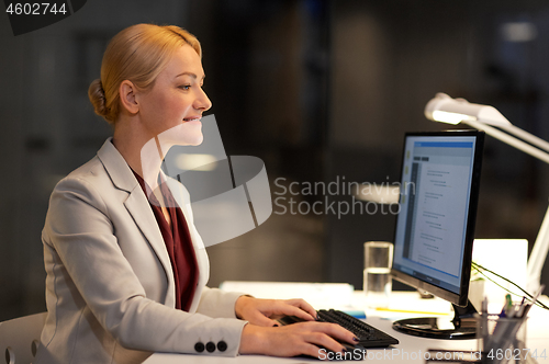 Image of businesswoman at computer working at night office