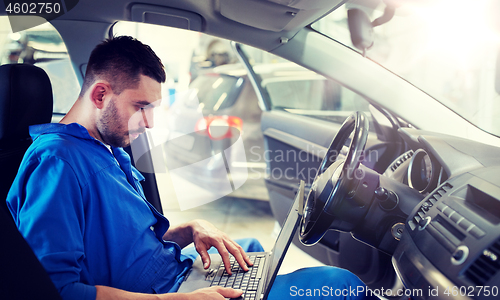 Image of mechanic man with laptop making car diagnostic