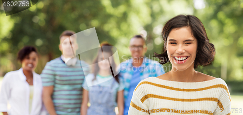 Image of happy woman winking at summer park with friends
