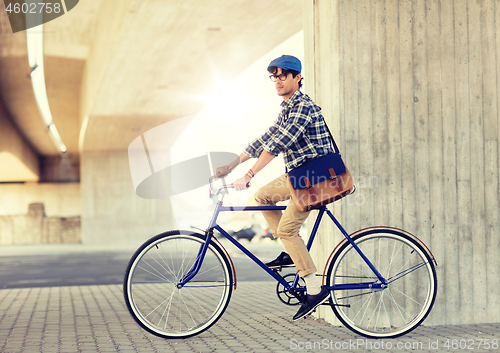 Image of young hipster man with bag riding fixed gear bike