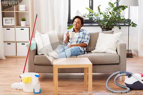 Image of woman drinking coffee or tea after cleaning home