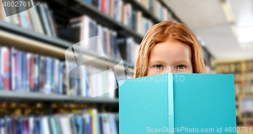 Image of smiling red haired girl reading book at library