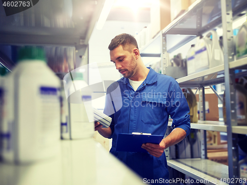 Image of auto mechanic with oil and clipboard at car shop