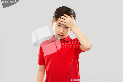 Image of sick boy in red t-shirt suffering from headache