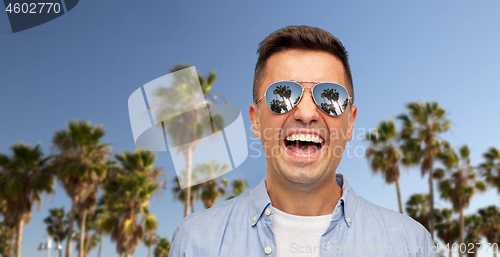 Image of laughing man in sunglasses over palm trees
